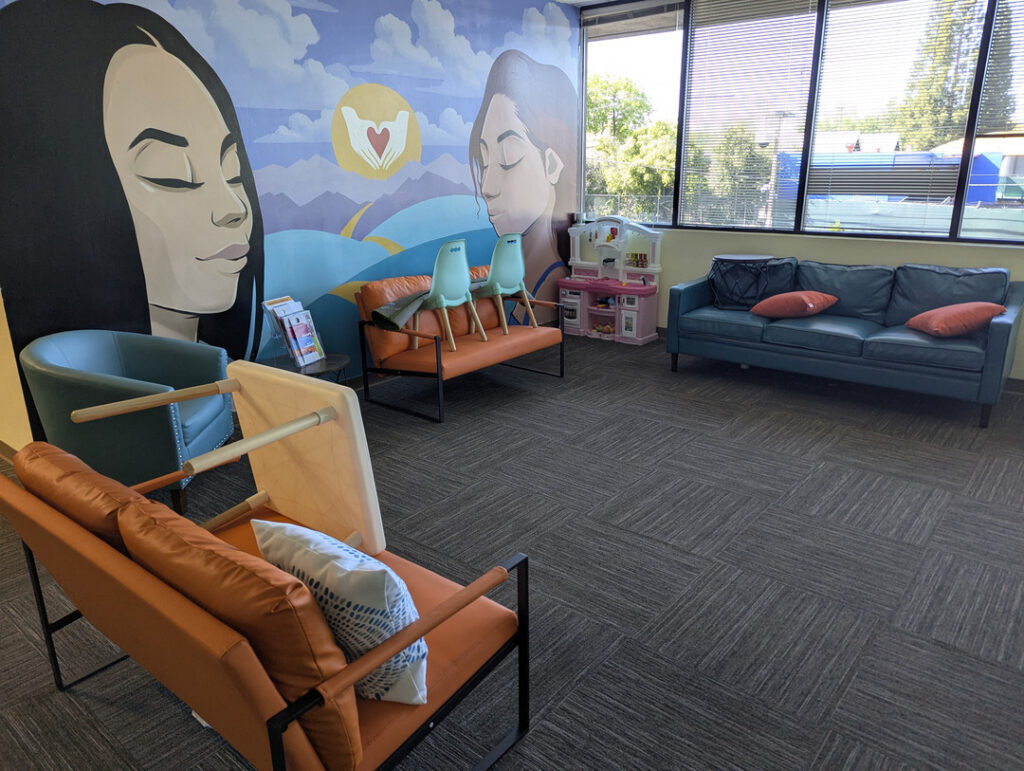 a waiting area with colorful seating and a mural on the wall soft lighting and a play area for children