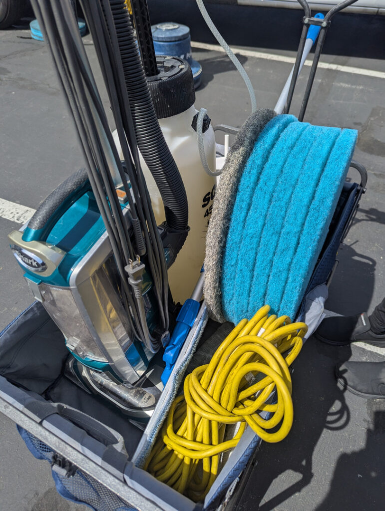 cleaning equipment with a vacuum machine hoses cleaning pads and extension cords organized in a carrying case
