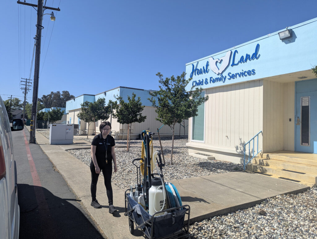 cleaning service preparing equipment outside a commercial building under clear blue skies