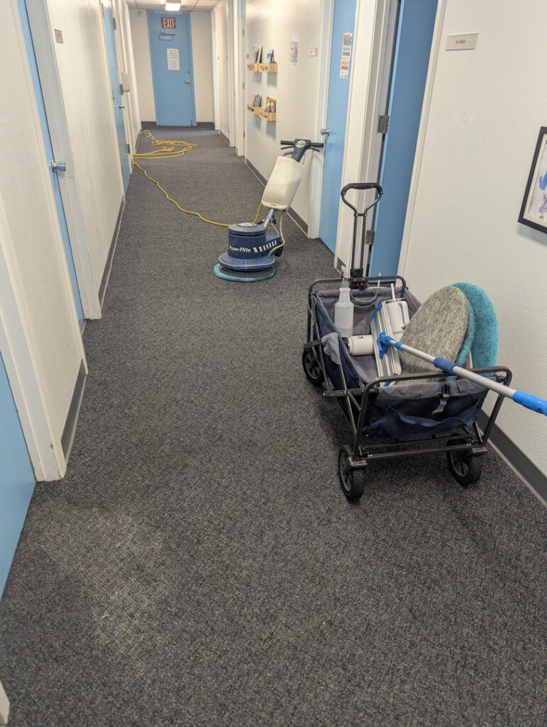 crystal clean carpet pros conducting carpet cleaning in a hallway using a cleaning machine and equipment on a cart