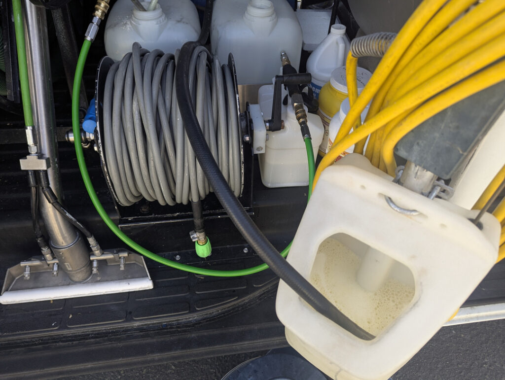 hosing and equipment for carpet cleaning with hoses and containers visible in a service vehicle setup