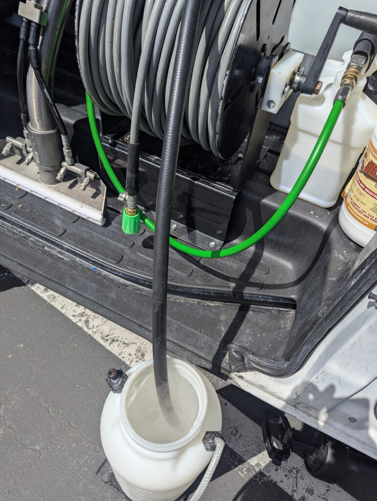 water tank and hose setup for carpet cleaning services with cleaning solution visible in container